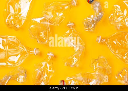 Viele gebrauchte Plastikflaschen auf orangefarbenem Hintergrund. Das Konzept der Verschmutzung des Planeten und der Ozeane durch Plastikmüll. Stockfoto