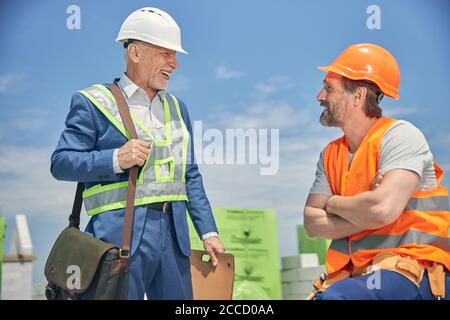 Fröhlicher älterer Mann, der einen Bauarbeiter anlächelt Stockfoto