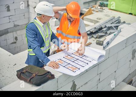 Bauingenieur, der einen verwirrten männlichen Arbeiter ansieht Stockfoto