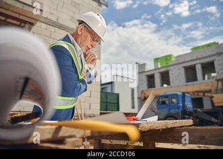 Mann in Brillen, der sich über seine Zeichnungen lehnt Stockfoto