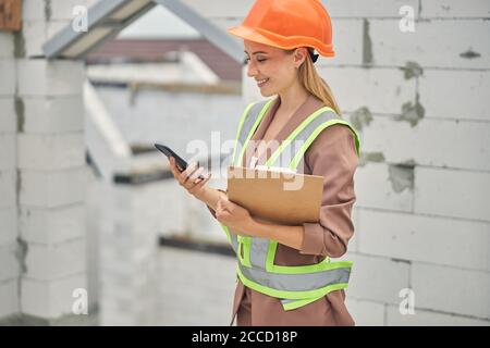 Zufrieden blonde Frau Ingenieur hält ein Klemmbrett Stockfoto