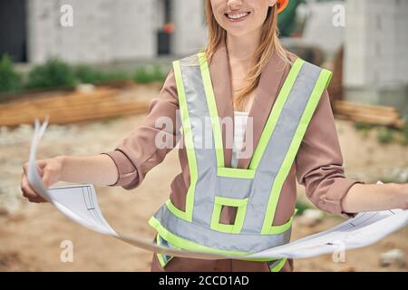 Lächelnder Ingenieur mit Blaupausen auf der Baustelle Stockfoto