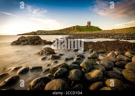 Dunstanburgh Castle schoss am frühen Morgen mit der Nordsee in der Bucht. Stockfoto