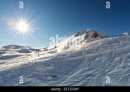 Landschaftlich schöner Blick auf schneebedeckten Berg an hellen sonnigen Wintertag. Schneebedeckte Gipfel gegen strahlend leuchtende Sonne am blauen klaren Himmel. Panorama Stockfoto