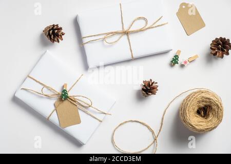 Weihnachtliche Hintergrund mit Geschenkschachteln, Kordelzug, Tannenzapfen auf weiß. Vorbereitung auf den Urlaub. Umweltfreundliche Weihnachtsgeschenke, Zero Waste Konzept. Stockfoto