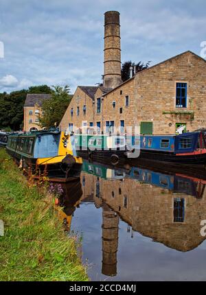 Spiegelungen eines historischen Mühlenschornsteins am Rochdale Canal an der Hebden Bridge, West Yorkshire. Die ehemalige Mühle wird heute als Gärtnerei genutzt. Stockfoto