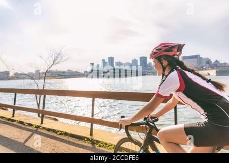 Urban Biking Mädchen Reiten Rennrad Radfahren in der Stadt. Glücklicher Radfahrer mit Downtown Hintergrund am St. Lawrence River, Montreal, Kanada Stockfoto