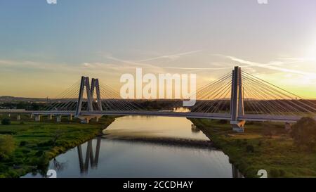 Monumentale, beleuchtete, moderne Doppelkabinenbrücke über die Weichsel in Krakau, Polen bei Sonnenuntergang. Industriebau aus Beton und Stahl Stockfoto