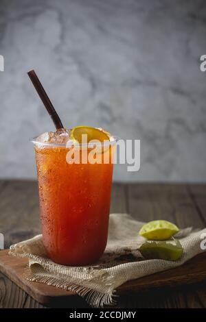 Eistee mit Zitronenscheibe in Plastikbecher auf Der hölzerne Hintergrund Stockfoto