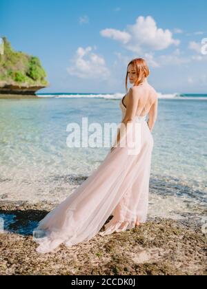 Juli 2020. Bali, Indonesien. Hochzeitstag der Rotkopfbraut im Hochzeitskleid am tropischen Strand. Frohe Hochzeit im tropischen Bali Stockfoto