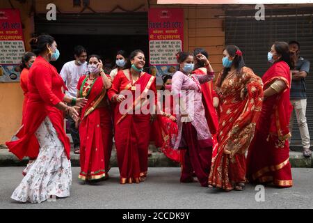 Kathmandu, Nepal. August 2020. Nepalesische Hindu-Frauen singen, tanzen und feiern während des Teej-Festivals in traditionellen Kostümen und tragen Gesichtsmasken als vorbeugende Maßnahme in der Krise des Coronavirus (COVID-19).während dieses Festivals beobachten Hindu-Frauen ein ganztägiges Fasten und beten für ihre Ehemänner und für ein glückliches Eheleben. Diejenigen, die unverheiratet sind, beten für einen guten Mann. Kredit: SOPA Images Limited/Alamy Live Nachrichten Stockfoto