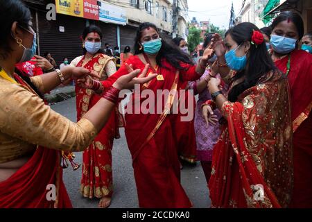 Kathmandu, Nepal. August 2020. Nepalesische Hindu-Frauen singen, tanzen und feiern während des Teej-Festivals in traditionellen Kostümen und tragen Gesichtsmasken als vorbeugende Maßnahme in der Krise des Coronavirus (COVID-19).während dieses Festivals beobachten Hindu-Frauen ein ganztägiges Fasten und beten für ihre Ehemänner und für ein glückliches Eheleben. Diejenigen, die unverheiratet sind, beten für einen guten Mann. Kredit: SOPA Images Limited/Alamy Live Nachrichten Stockfoto