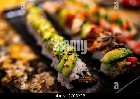 Sushi Rolls im Restaurant. Luxus-sushi mit Avocado und Aal Belag, Regenbogen Maki, Thunfisch, Tobiko, Sesam. Japanisches Essen. Stockfoto