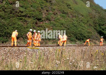 Eine Gruppe, oder Bande, oder Netwok Rail, Arbeiter, die Wartungsarbeiten auf einer Live-Bahnstrecke. Die Arbeiter räumen Schutt von der Strecke Stockfoto