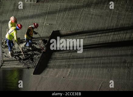 Austin, TX USA 25. Juli 2020: Betonarbeiter benutzt einen Elektroestrich, um Beton im Parkhaus eines 53-stöckigen Gebäudes während einer Nacht in der Innenstadt von Austin, TX, zu glätten. Trotz der landesweiten COVID-19-Pandemie und des Staates, der mit über einer halben Million Fällen und über 10,000 Todesfällen heimgesucht wird, werden in Texas weiterhin riesige Bauprojekte unvermindert durchgeführt. Stockfoto