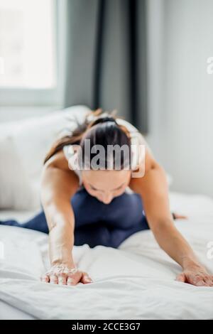 Junge schlanke kaukasische Frau Stretch-Beine tun Yoga-Übungen, flexible sportliche Frau auf geistige und körperliche Gesundheit konzentriert Stockfoto