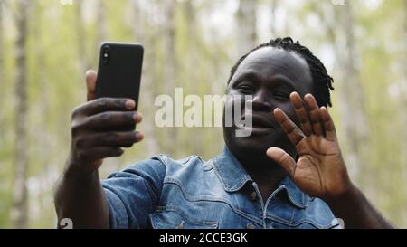 Afrikanischer Mann nimmt Selfies oder mit Videocall auf seinem Smartphone in der Natur. Hochwertige Fotos Stockfoto