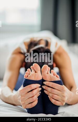 Nahaufnahme von jungen weiblichen Beinen während der Soing-Übungen auf dem Bett zu Hause, gesunde Lebensweise und Yoga-Konzept Stockfoto