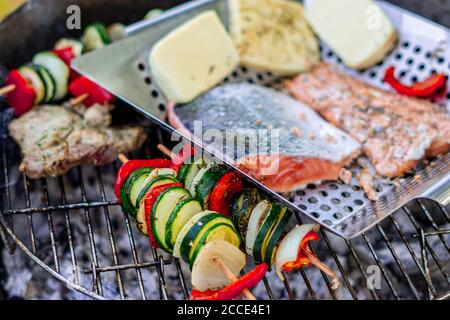 Grillen von Gemüsespießen und Fisch Stockfoto