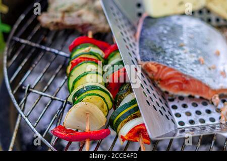 Grillen von Gemüsespießen und Fisch Stockfoto