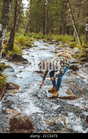 Junger Wanderer zieht kaltes Wasser in seine Tasse, volle Seitenansicht photo.break Stockfoto