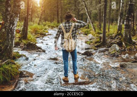 Mann wird Vergnügen vom Trinken des kalten Wassers des Stromes, Rückansicht voller Länge Foto.Urlaub Stockfoto