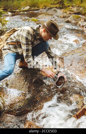Junger Wanderer, der Wasser zieht, um am Campingplatz zu trinken, Urlaub, Wochenende. Nahaufnahme Foto Stockfoto