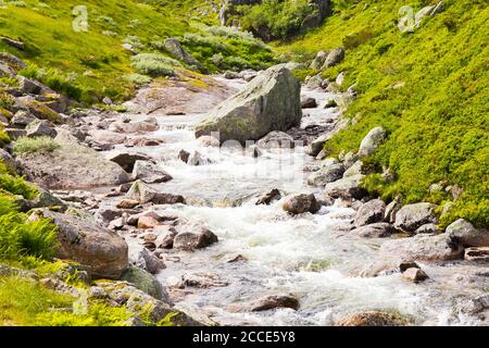 Schöne Aussicht auf den Bergfluss in der Nähe der Straße, gegen die holzigen Berge, aus einem auftauenden Gletscher. Der Anfang berühmt von Wasserfall Stockfoto