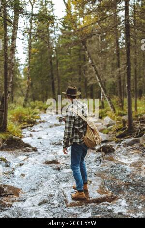 Tourist tragen Hut, Backpackm jeansm kariert Hemd genießen kaltes Wasser, Rückansicht in voller Länge Foto, Reise, Zeitvertreib Stockfoto