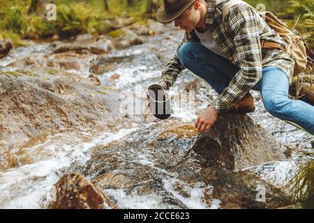 Junger Mann nimmt Wasser aus dem Fluss, Nahaufnahme beschnitten Seitenansicht Foto Stockfoto