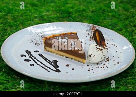 Gesalzene Karamelltarte mit Schlagsahne und grünem Hintergrund Stockfoto