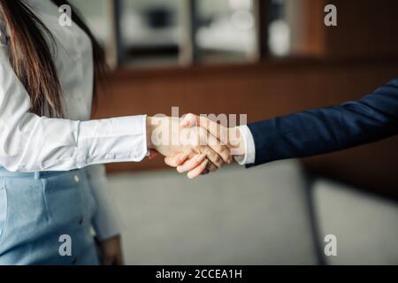 Zwei kaukasische Geschäftsfrauen in Bürokleidung, die beim Treffen die Hände schütteln, während sie eine Partnerschaft schließen, konzentrieren sich auf die Hände Stockfoto