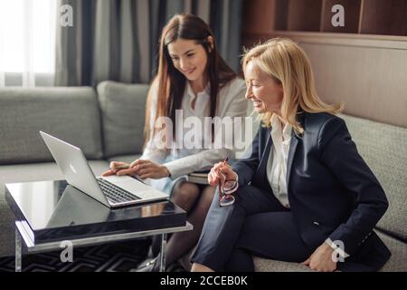 Brunette Mädchen Anordnung Treffen mit weiblichen Tieflyer oder Steuerberater im Büro. Blonde Steuerberater Beratung Client beim Zeigen auf Laptop-Bildschirm. Stockfoto