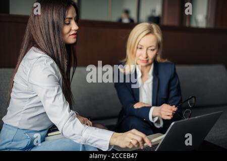 Zwei elegante klassische Business-Frauen, weibliche Partner in formeller Kleidung mit Gespräch, Planung Projektbudget während sitzen auf Couch im Büro Stockfoto