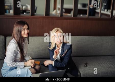 Brunette Mädchen Anordnung Treffen mit weiblichen Tieflyer oder Steuerberater im Büro. Blonde Steuerberater Beratung Client beim Zeigen auf Laptop-Bildschirm. Stockfoto