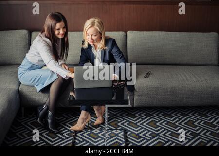 Konzept für kleine Unternehmen. Junge kreative Kleinunternehmen arbeiten mit neuen Startup-Projekt im modernen Büro. Zwei junge Frauen sitzen auf dem Sofa und Stockfoto