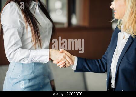 Haben Sie einen Guten Tag. Zwei weibliche Mitarbeiter begrüßen, trennen oder gratulieren sich gegenseitig, während sie sich im Büro treffen. Begrüßung, Begrüßung, Abschiedskonzept Stockfoto