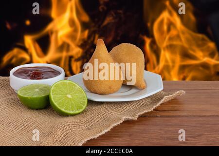 Coxinha. Traditionell gebratenes brasilianisches Essen mit Huhn. Hintergrund mit unfokussem Feuer Stockfoto