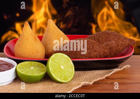 Coxinha und Kiba. Traditionelle frittierte brasilianische Küche. Hintergrund mit unfokussem Feuer. Speicherplatzkopie Stockfoto