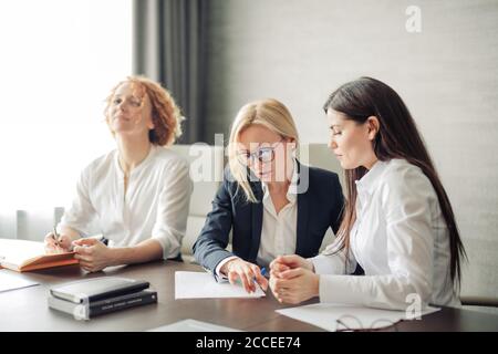 Drei kaukasische Studentinnen oder Praktikanten in weißen Hemden, Praktikantin mit Laptop, Arbeit am pc, Studium in der Universität, Eingabe, Surfen Websites, AP Stockfoto