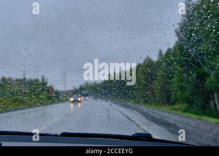 Regentropfen auf einem Autoglas an regnerischen Tagen im ländlichen Raum. Stockfoto