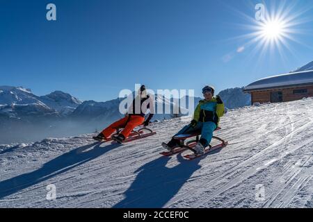 Europa, Schweiz, Wallis, Belalp, Mutter und Sohn Rodeln an einem sonnigen Wintertag in den Walliser Alpen Stockfoto