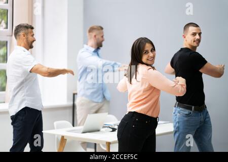 Gruppe der Glückliche junge Geschäftsleute tun Stretching Übung im Büro Stockfoto