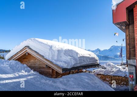 Europa, Schweiz, Wallis, Belalp, Blick auf ein schneebedecktes Dach und ein Gleitschirm im Hintergrund Stockfoto