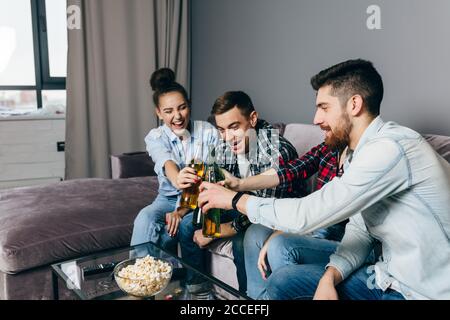 Glückliche frinds klirrenden Flaschen. Junge glückliche Menschen toasten zu Gesundheit und Glück. Close up Seitenansicht Foto Stockfoto