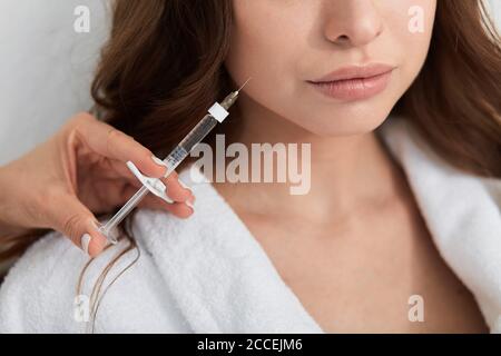 Nahaufnahme beschnittenes Foto von einer Frau, die Gesichts-Füllstoff-Injektionen erhält, sich verjüngende Hautpflege-Behandlung erhält, sich Injektion in ihre Lippen bekommt. Stockfoto