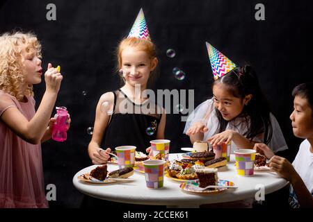 Kinder haben Spaß mit Seifenblasen im Urlaub. Isolierte schwarze Hintergrund. Happy Event. studio erschossen. Kindheit. Stockfoto