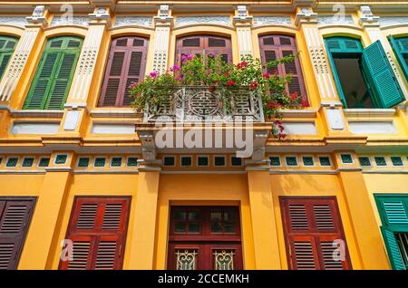 Fassade im französischen Kolonialstil und Balkon mit Blumen und Fenstern, Hanoi City, Nordvietnam. Stockfoto