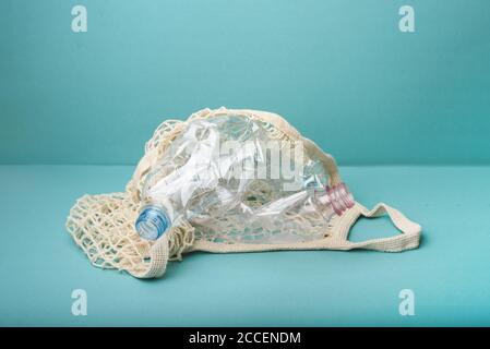 Netztasche mit Plastikflaschen auf blauem Hintergrund. Unsere Erde aufräumen. Kein Abfall, Kunststoff-freies Konzept. Nachhaltiger Lebensstil. Stockfoto