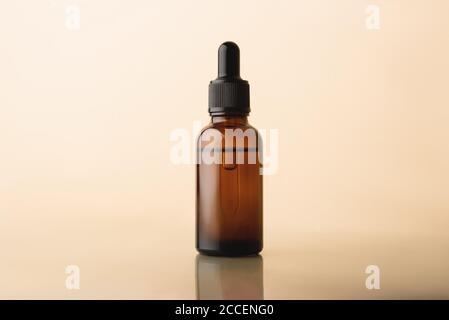 Serumglasflasche mit Pipette auf dem beigen reflektierenden Hintergrund. Natürliches organisches Spa Kosmetikkonzept. Vorderansicht. Stockfoto